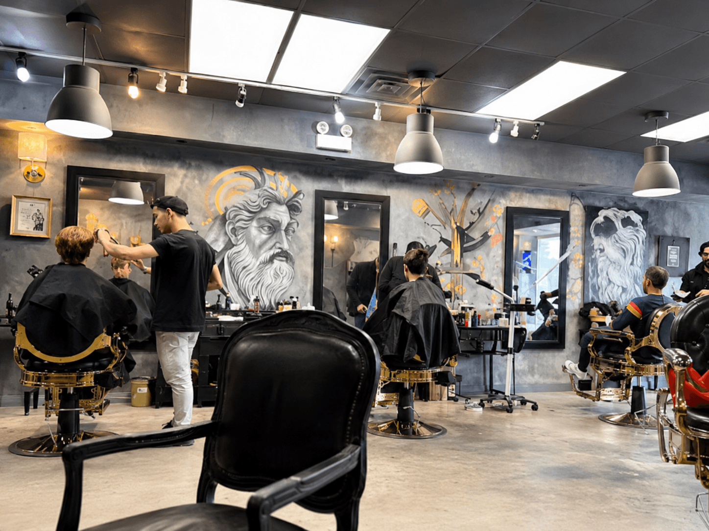 Interior of Lui's Barber Shop — hand-painted Greek murals on concrete walls, barbers at work
